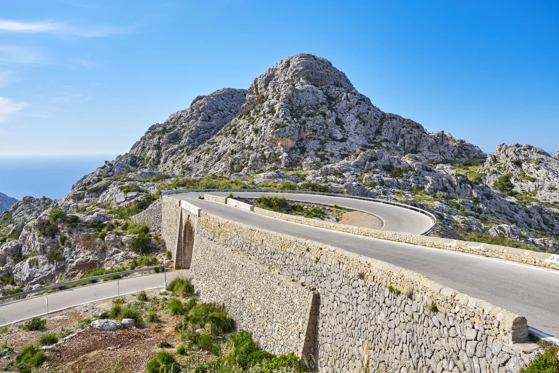 Winding mountain road with stone retaining wall overlooking the sea, Sa Calobra, Mallorca.