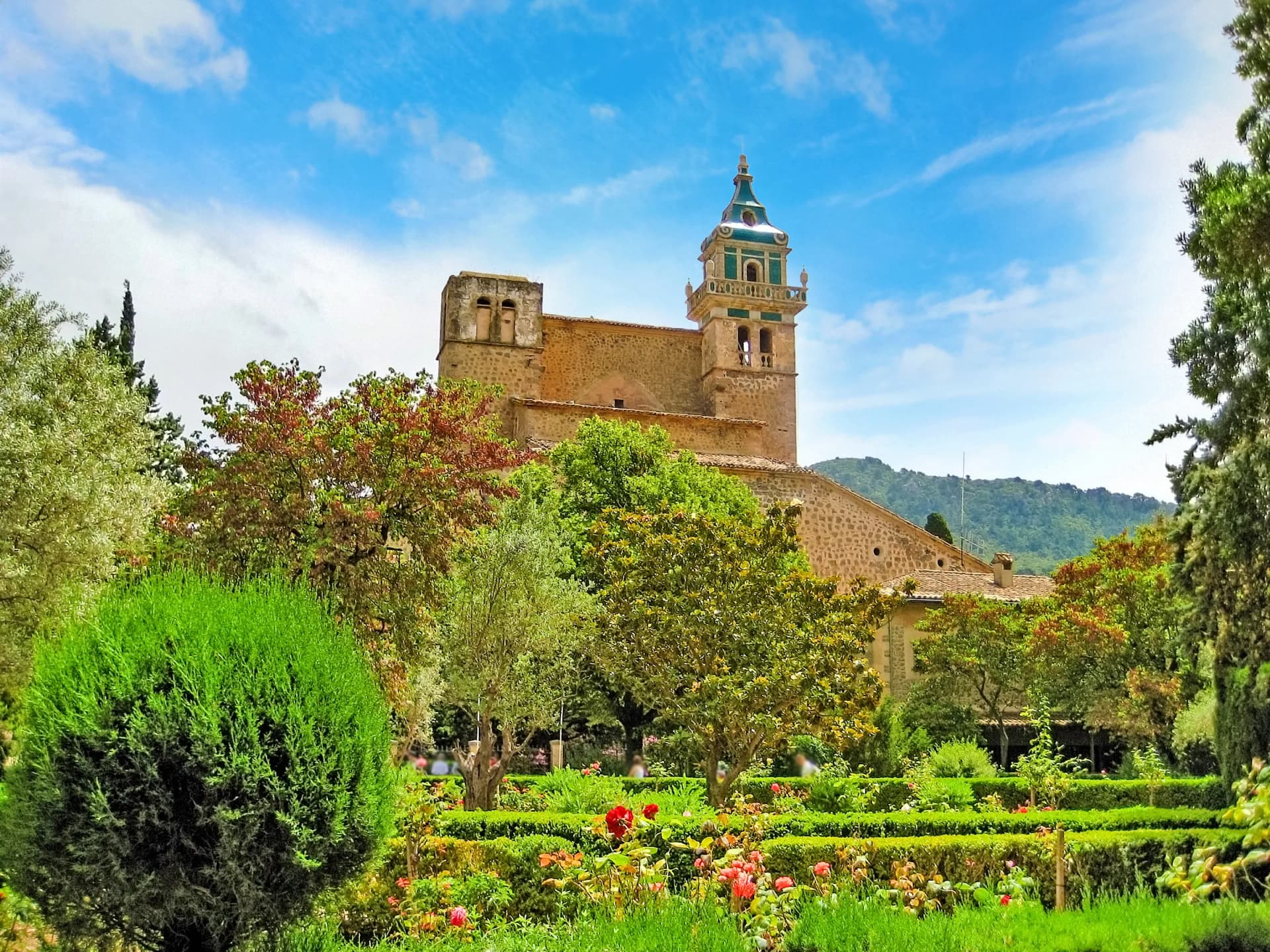 Monastery of Valldemossa Majorca Spain bell tower above lush green gardens and trees.