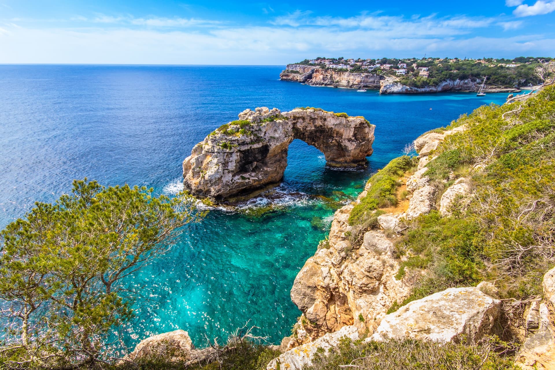 Natural stone arch in turquoise Mediterranean sea water near rocky coastline in Mallorca