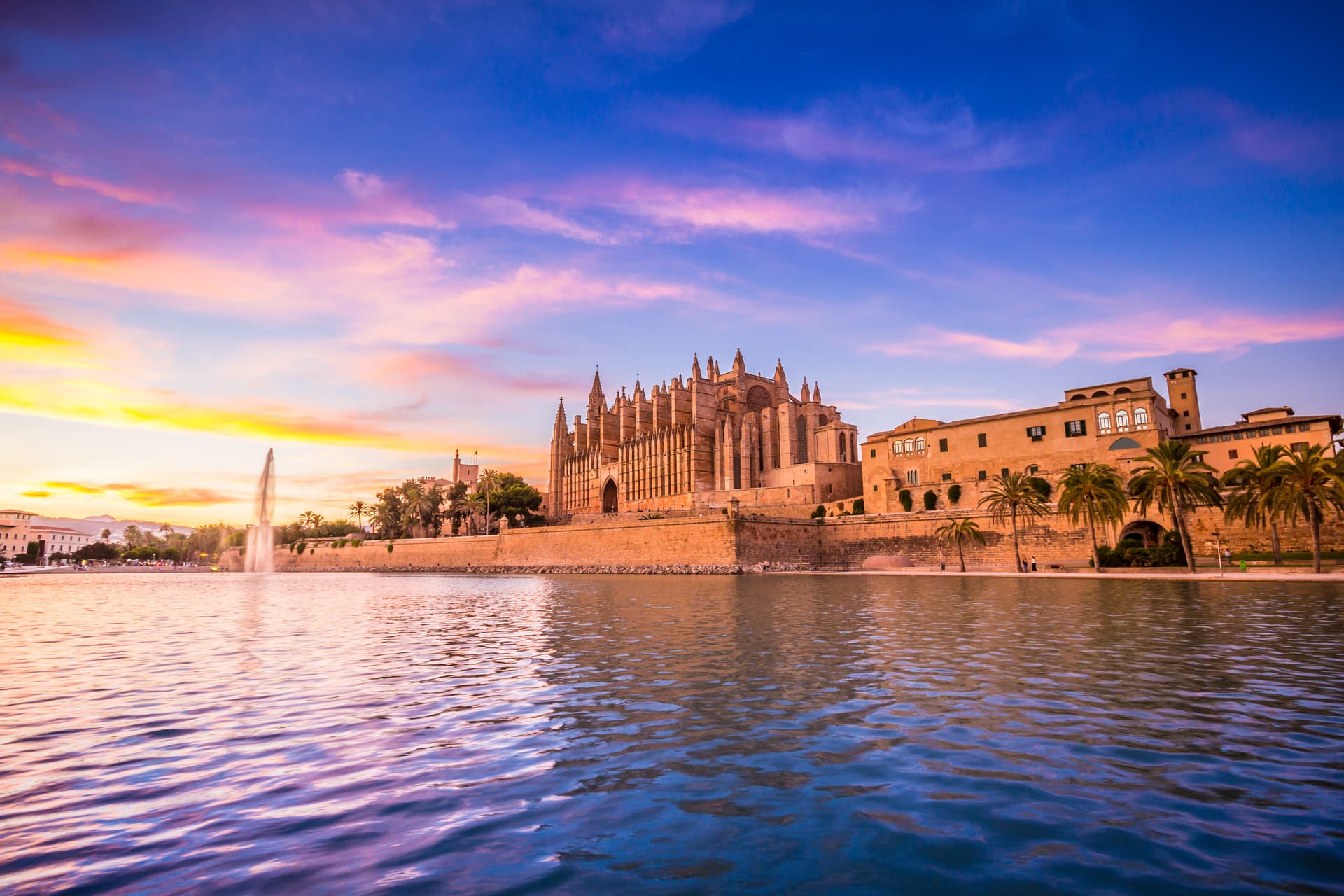 Palma Cathedral and waterfront with fountain at sunset in Mallorca, Spain.