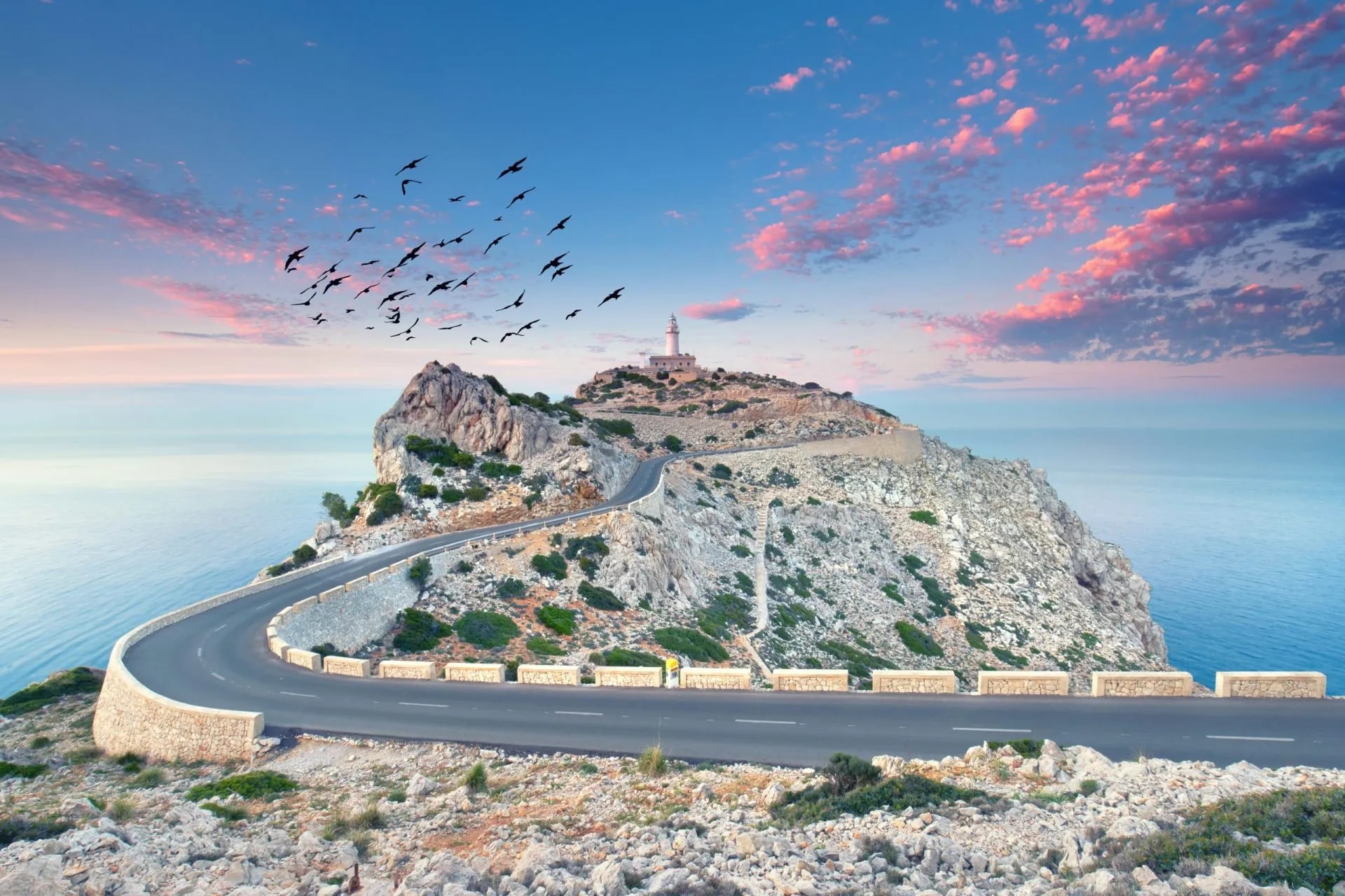 Winding road up rocky cliff to lighthouse at Cap de Formentor, Mallorca at sunset