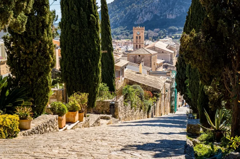 Carrer del Calvari staircase lined with cypress leads 365 steps downstairs to the old town of Pollensa with great view over rooftops to the church Santa Maria dels Àngels and mountain Puig de Maria.